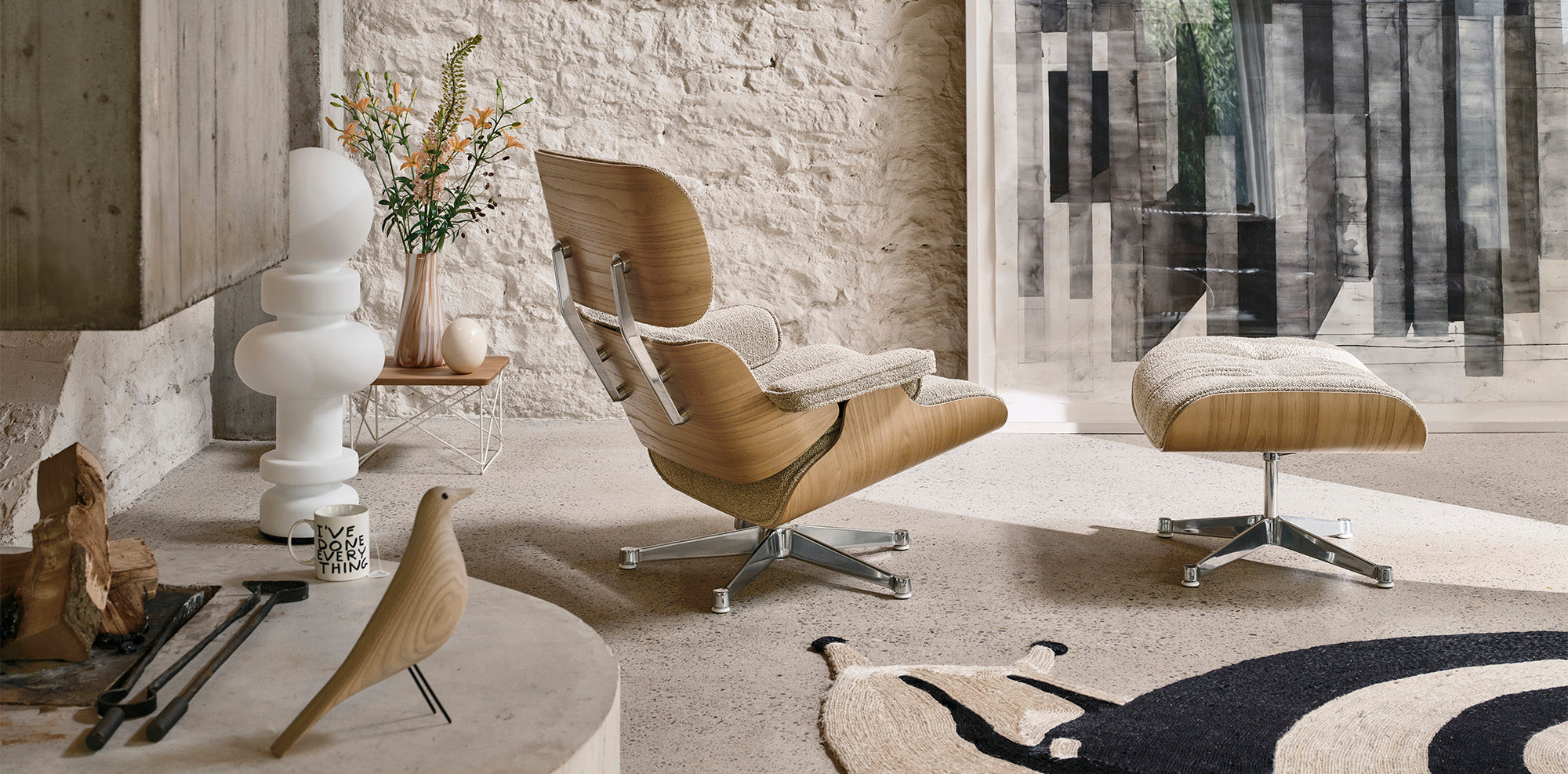 Modern living room with a brown chair and ottoman, white table, and decorative elements. Vitra Eames Lounge chair and house bird and ltr coffee table