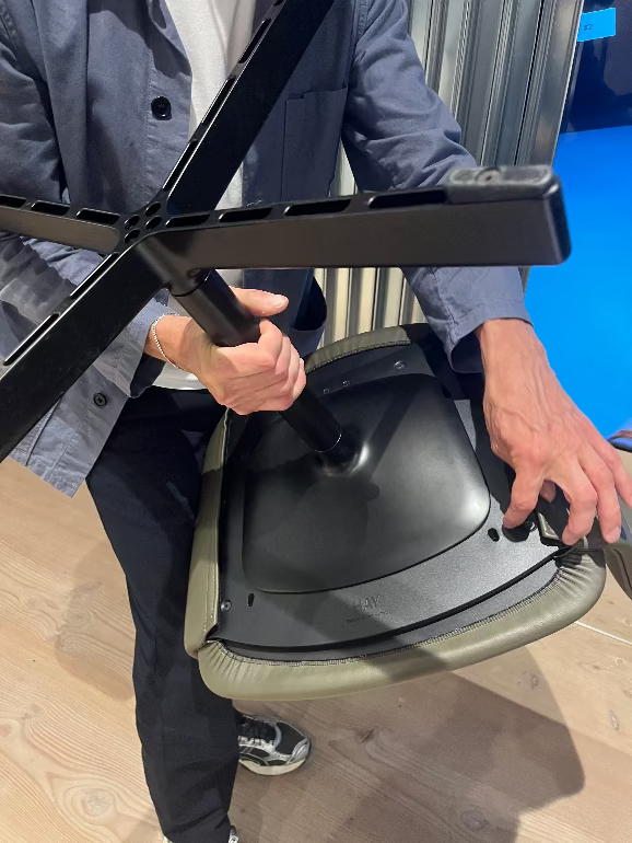 Julien Renault furniture designer for HAY holding a black and green Layout office chair to show the metal base