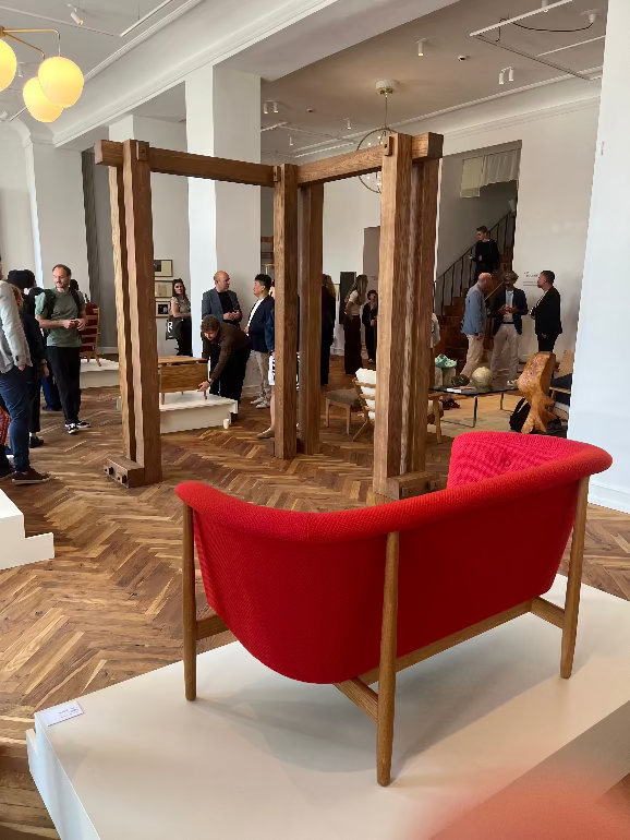 Red sofa with wooden frame in a room with people and mirrors at the Carl Hansen Copenhagen store during 3daysofdesign 2025 festival. Nana ditzel ND52 sofa