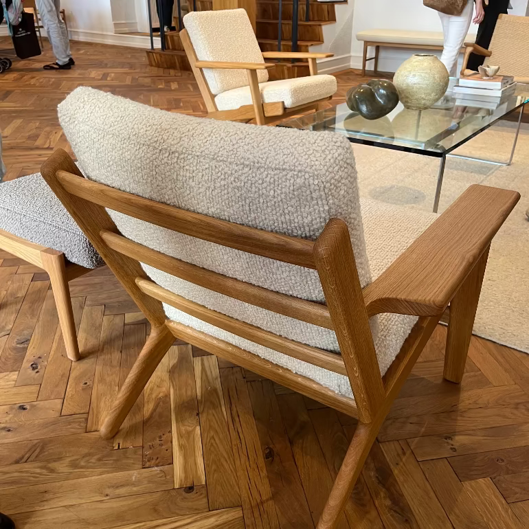 Ch290 Wooden lounge chair with white cushion by hans wegner for carl hansen on a wooden floor in an indoor setting in copenhagen
