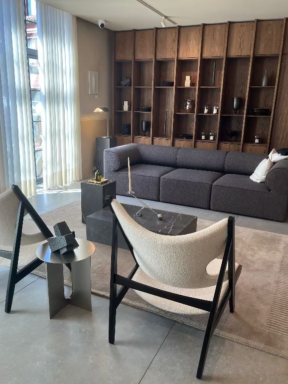 Modern hotel room with gray sectional Eave sofa, Knitting chairs, and a bookshelf. All in Audo House, Copenhagen