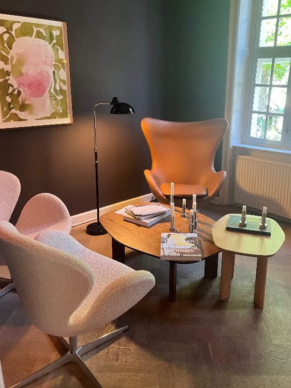 Modern living room with two Fritz Hansen swan chairs, egg chair , a coffee table, and a lamp at Orangeriet restaurant in copenhagen