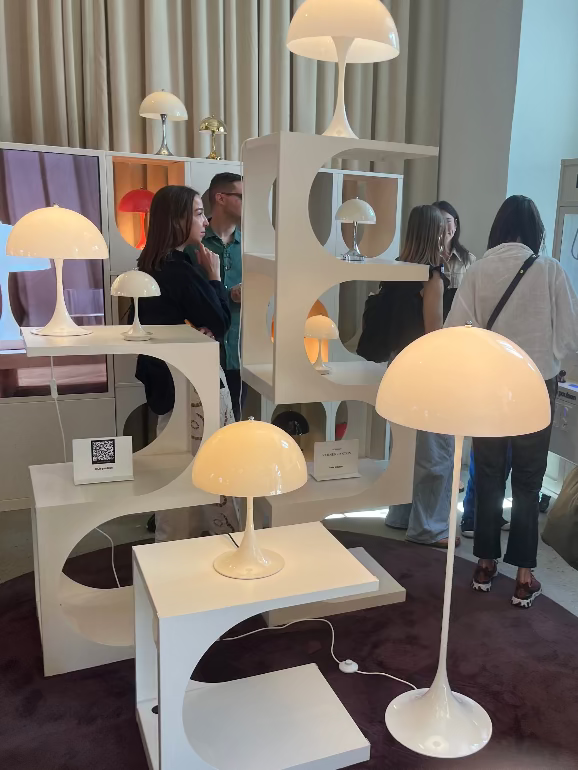 Display of modern lamps at a showroom with people observing. Louis Poulsen Copenhagen showroom during 2025 3 Days of Design