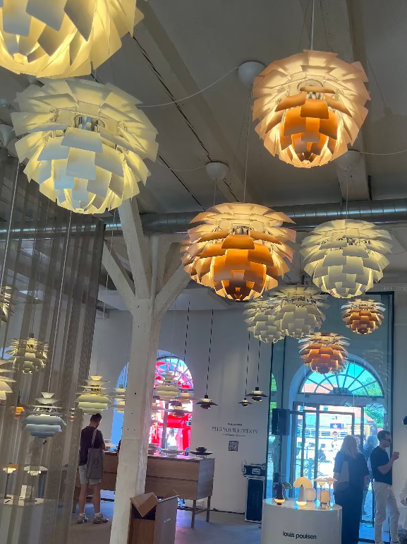 Louis Poulsen Artichoke Modern pendant lights hanging in a showroom with people and furniture in the background