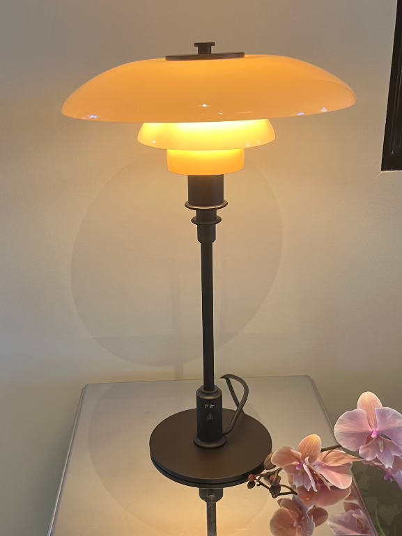 Louis Poulsen PH3/2 Dusty Terracotta Table lamp 2025 special edition on a reflective surface with flowers in the foreground
