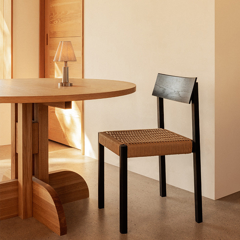 Audo Puffin Dining Table Round — lifestyle, with Mauro Dining Chair Paper Cord and Admiral Portable Table Lamp