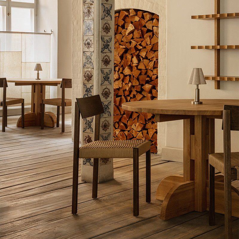 Audo Puffin Dining Table Round — lifestyle, with Mauro Dining Chair Paper Cord and Admiral Portable Table Lamp