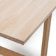 Close-up of a light natural wood tabletop corner with visible wood grain and a matching wooden leg, photographed against a clean white background.