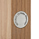A close-up of a round brushed-metal emblem reading 'REPUBLIC OF Fritz Hansen' mounted on a light wood surface.