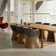 A modern wooden conference table with six matching upholstered chairs in a bright, contemporary office interior with glass walls and tiled floors.