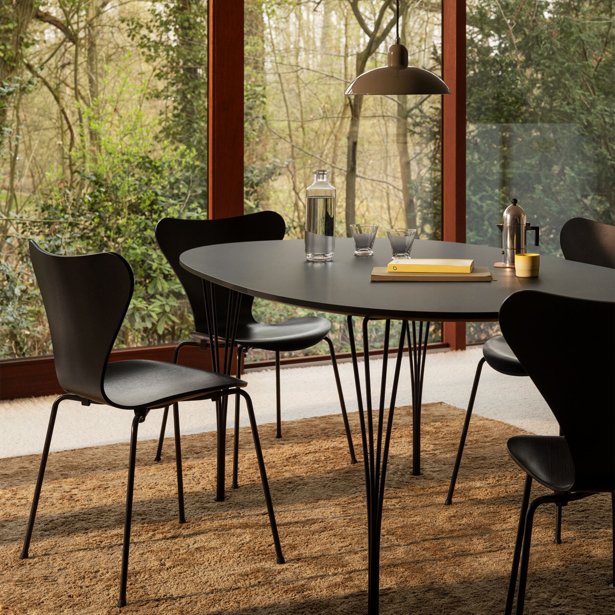 Fritz Hansen Superellipse Dining Table — lifestyle, dining room with black Series 7 chairs and Kaiser idell pendant