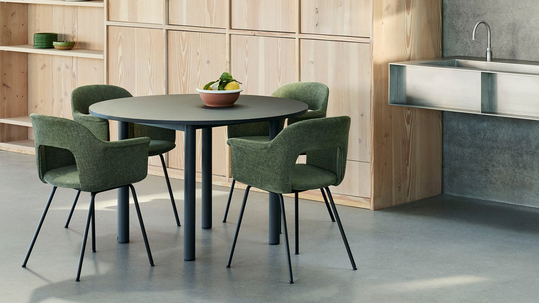 Modern kitchen with a round table and green chairs in a minimalistic setting. Hay Layout upholstered dining chair and Annex dining table