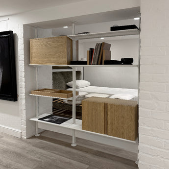 A contemporary Pira G2 floor-to-ceiling shelving unit with metallic frames and wooden shelves.