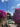 People sitting under purple flowers with a tall amusement park ride in the background at Tivoli Gardens in Copenhagen 2025