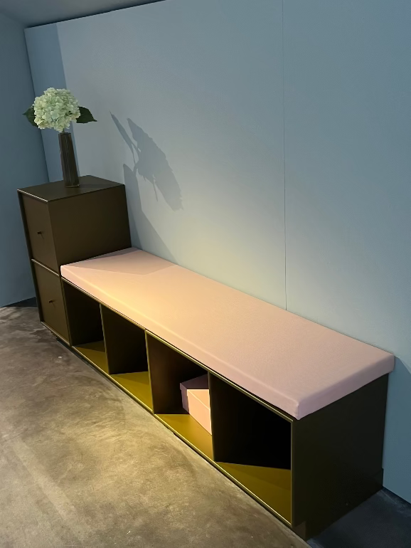 Montana System storage. Modern bench with a cushion against a light blue wall in an indoor setting.