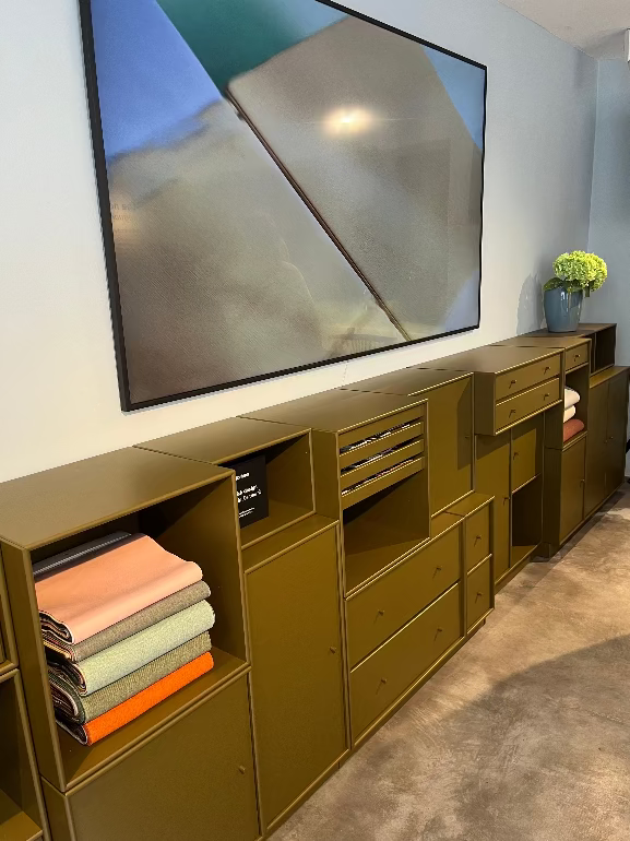 Montana storage system. Modern olive green entertainment console with a large flat-screen TV above it in a living room setting.