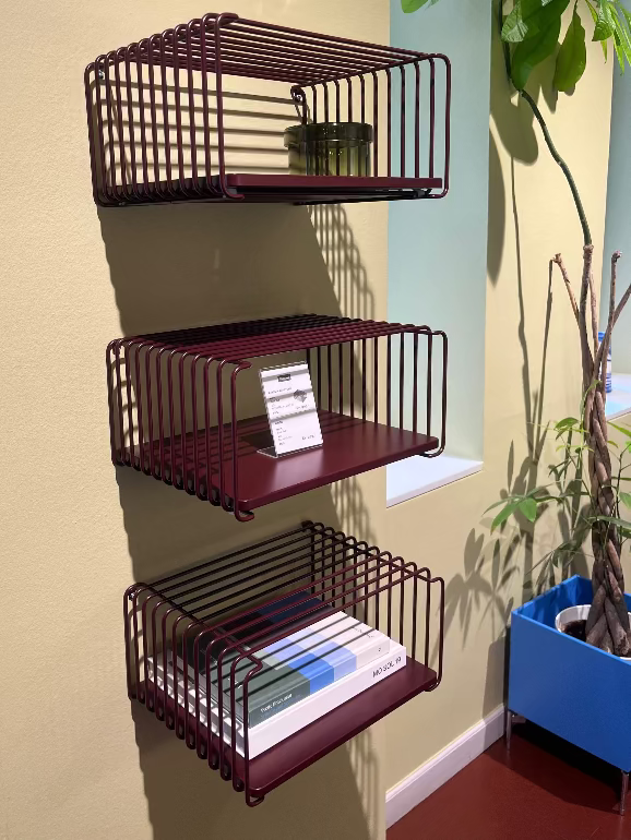 Montana Panton wire. Set of three metal wall shelves against a wall with a plant in the background.