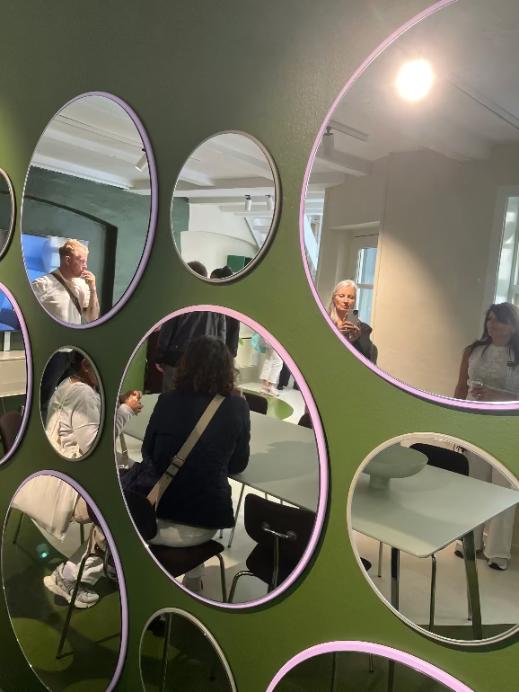 Montana wall mirrors at Copenhagen store.Multiple circular mirrors on a green wall reflecting people in a room.