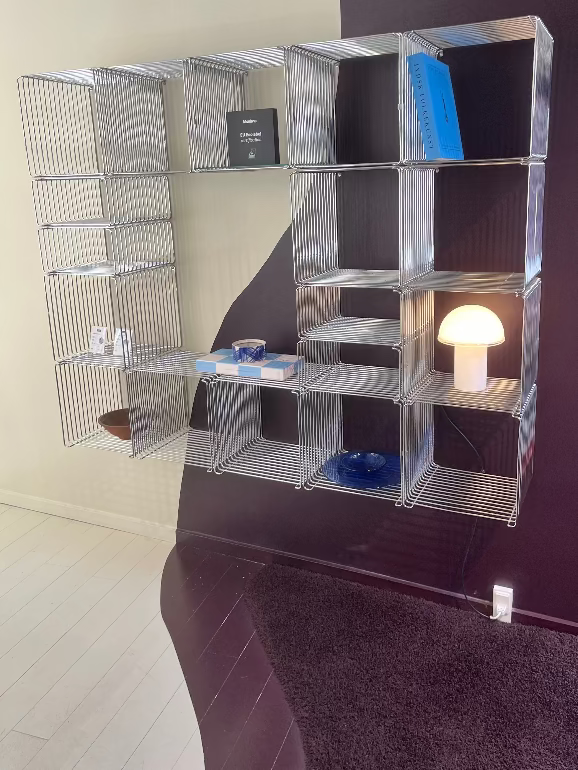 Montana Panton Metal wire shelving with various items against a dark wall