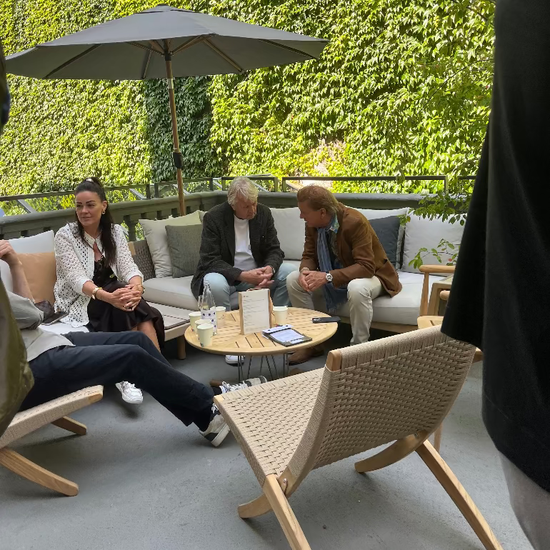 Carl Hansen outdoor furniture with People sitting on outdoor furniture with a green wall in the background