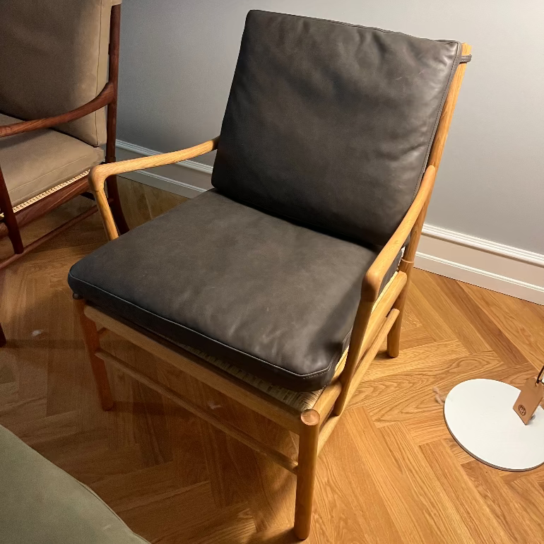 Colonial Chair with dark cushions on a wooden floor against a gray wall