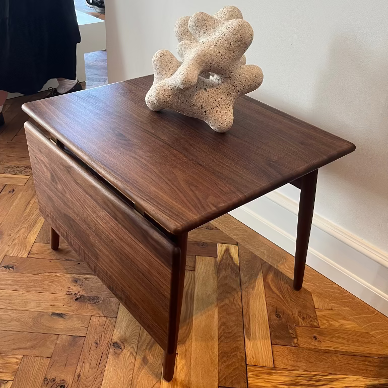 ND55 extendable wooden walnut coffee table by Nanna Ditzel for Carl Hansen with a decorative object on a wooden floor