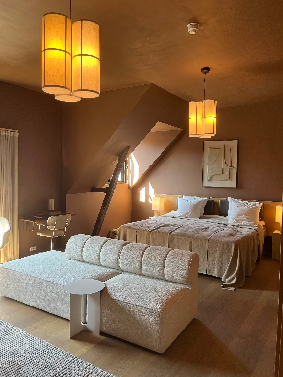 Modern bedroom with a bed, sofa, and decorative lighting fixtures at the Audo hotel in Copenhagen