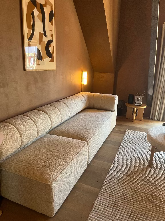 Beige Audo Copenhagen Eave sectional sofa in a living room with abstract art and a lamp in Denmark