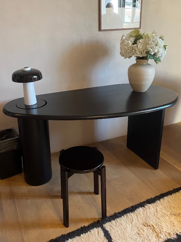 Modern Eclipse black desk / dressing table with a stool and vase of flowers in a room. Audo Copenhagen hotel
