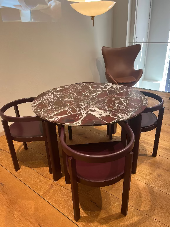 Fritz Hansen's Round After marble table with four matching chairs in a room with wooden flooring and Egg chair in background
