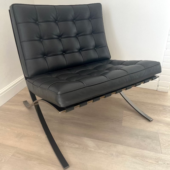 Knoll Barcelona Bauhaus special edtion lounge chair. Black leather chair on a wooden floor with a white wall background