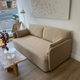 Audo Offset 2 seater sofa in Boucle 02 - A modern beige fabric scandi style sofa in a contemporary living room setting, positioned next to a marble-top coffee table with a lit candle, with a large abstract art print on the wall behind it at Innes showroom in Hessle, UK