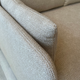 Close-up of a textured light beige Audo Boucle 02 fabric sofa cushion and armrest, showing the woven upholstery detail. Taken in Innes gallery on Audo Offset sofa.