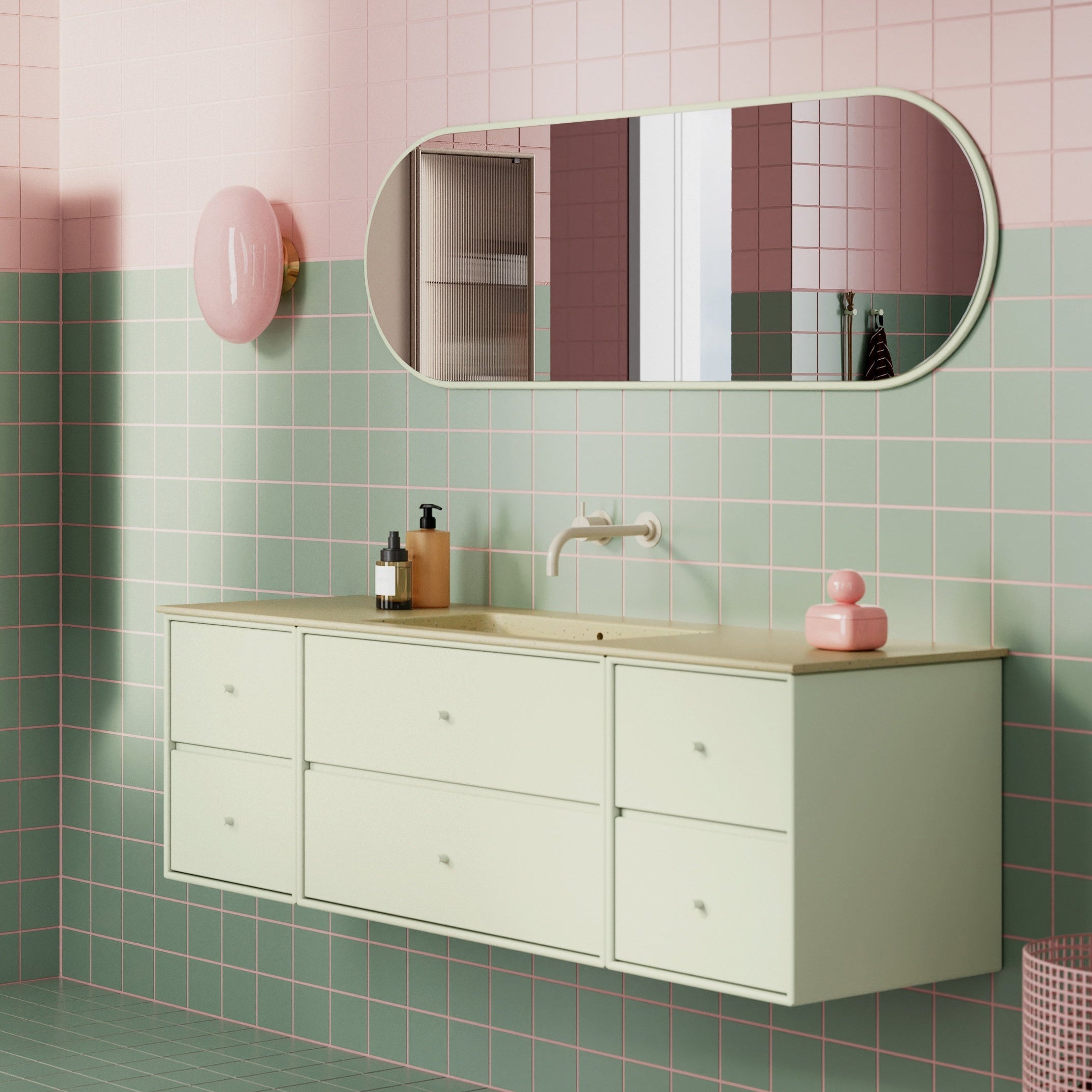 Bathroom with pink and green tiled walls, a white vanity, and a round mirror.