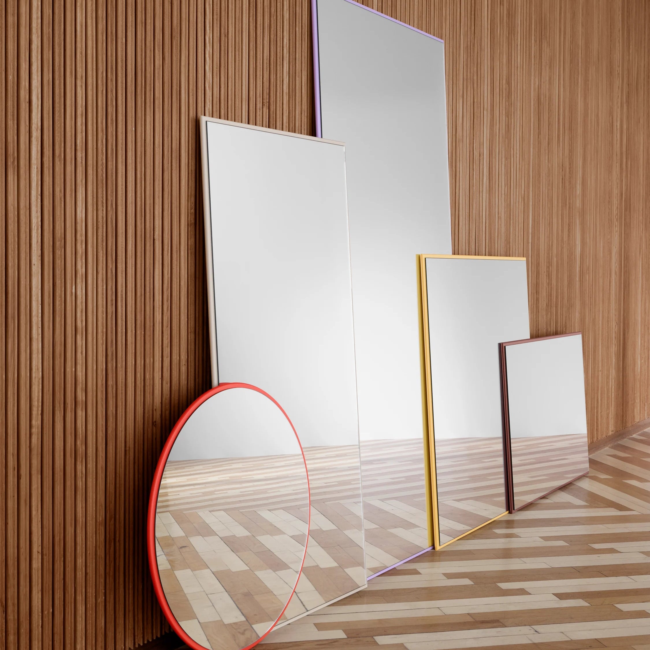 Set of Montana mirrors with different frames on a wooden floor and wall.